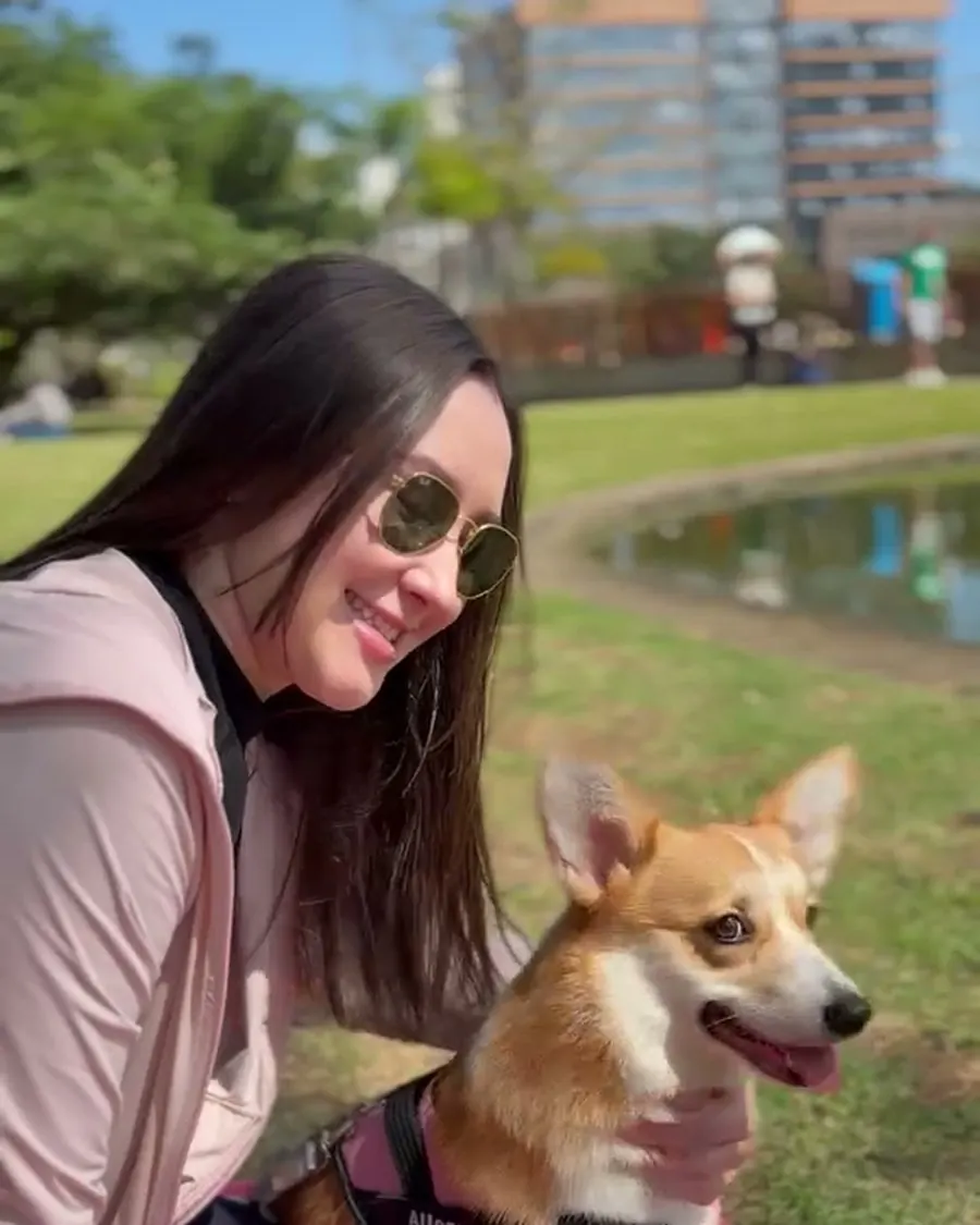 Tutora sorrindo com o corgi no parque