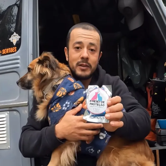 Tutor com o cachorro no colo mostrando a coleira